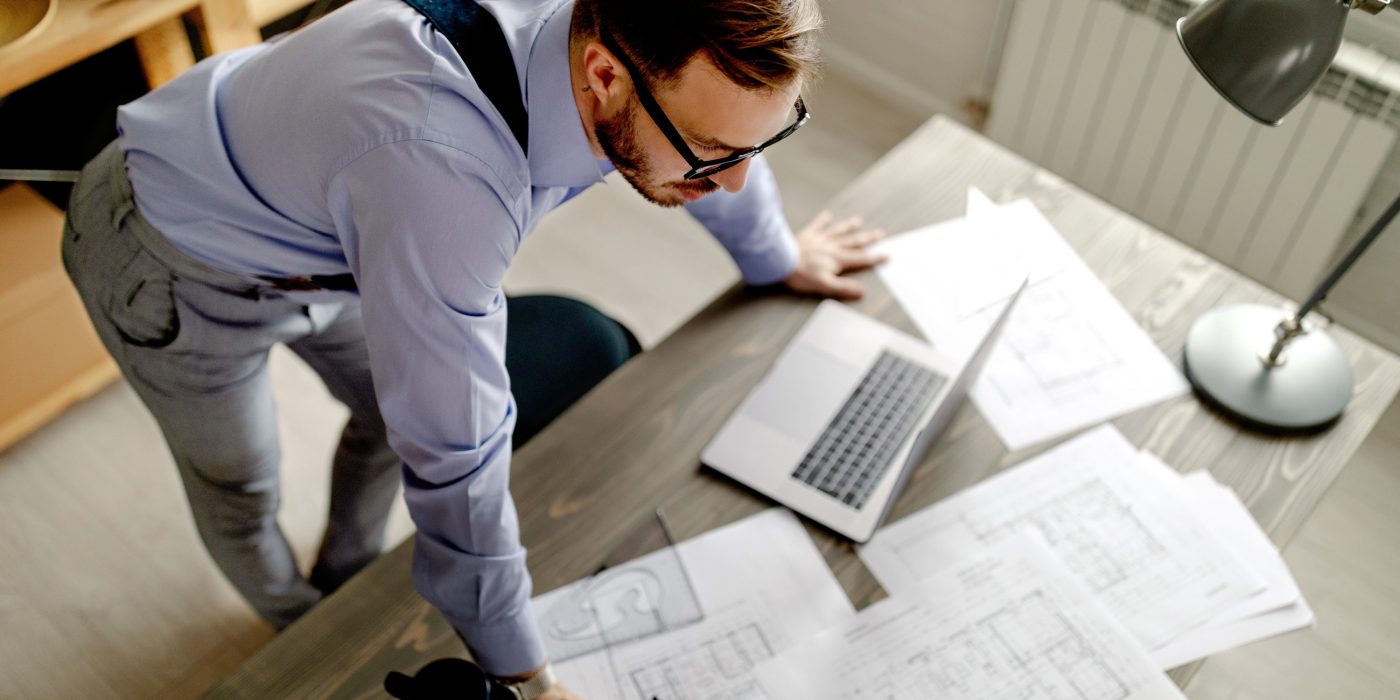 Top view of young architect, thinking about new project, he is lean on the table. Work at home.