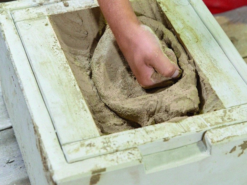Worker preparing clay to a brick in a hand form