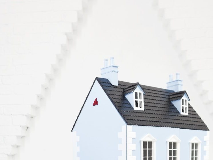 Relaxed and smiling girl sitting next to doll house in attic loft