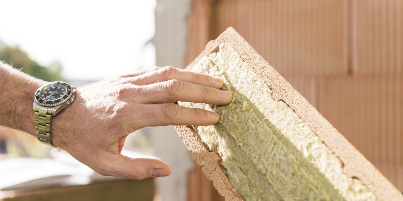 Hand touching mineral wool of internal insulation filled clay block