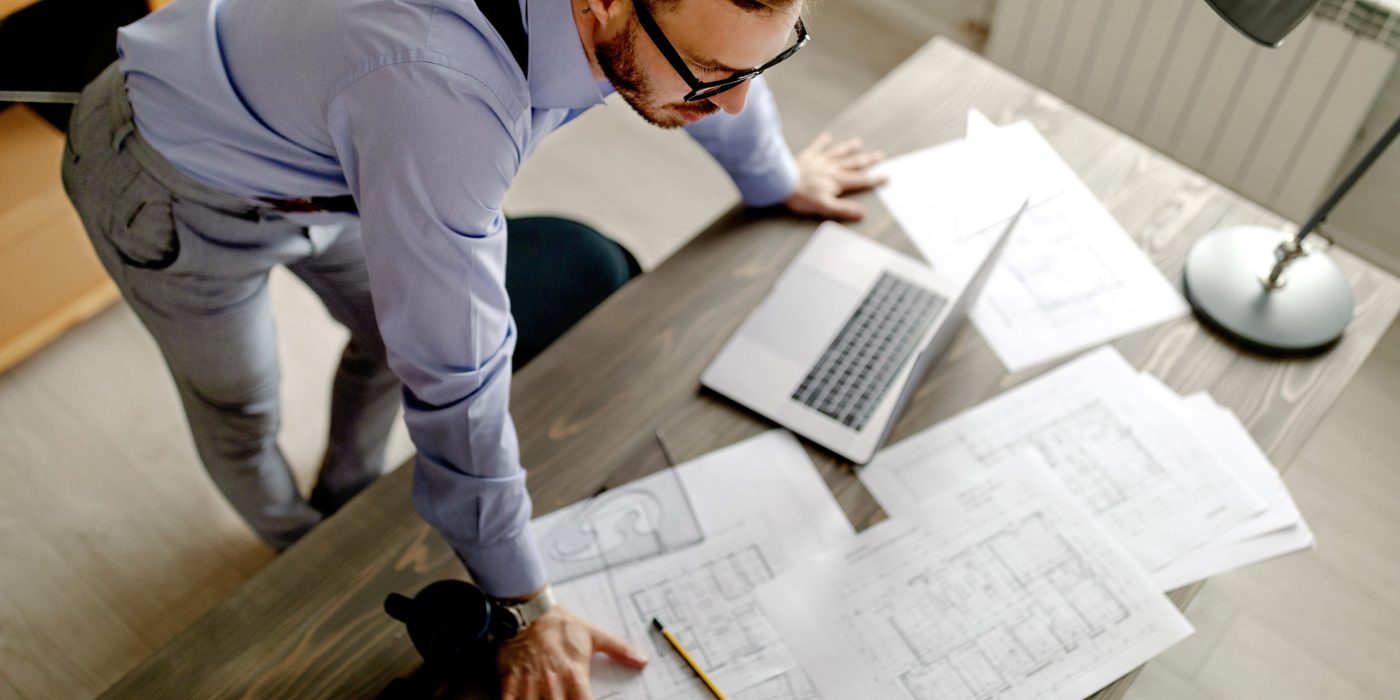 Top view of young architect, thinking about new project, he is lean on the table. Work at home.