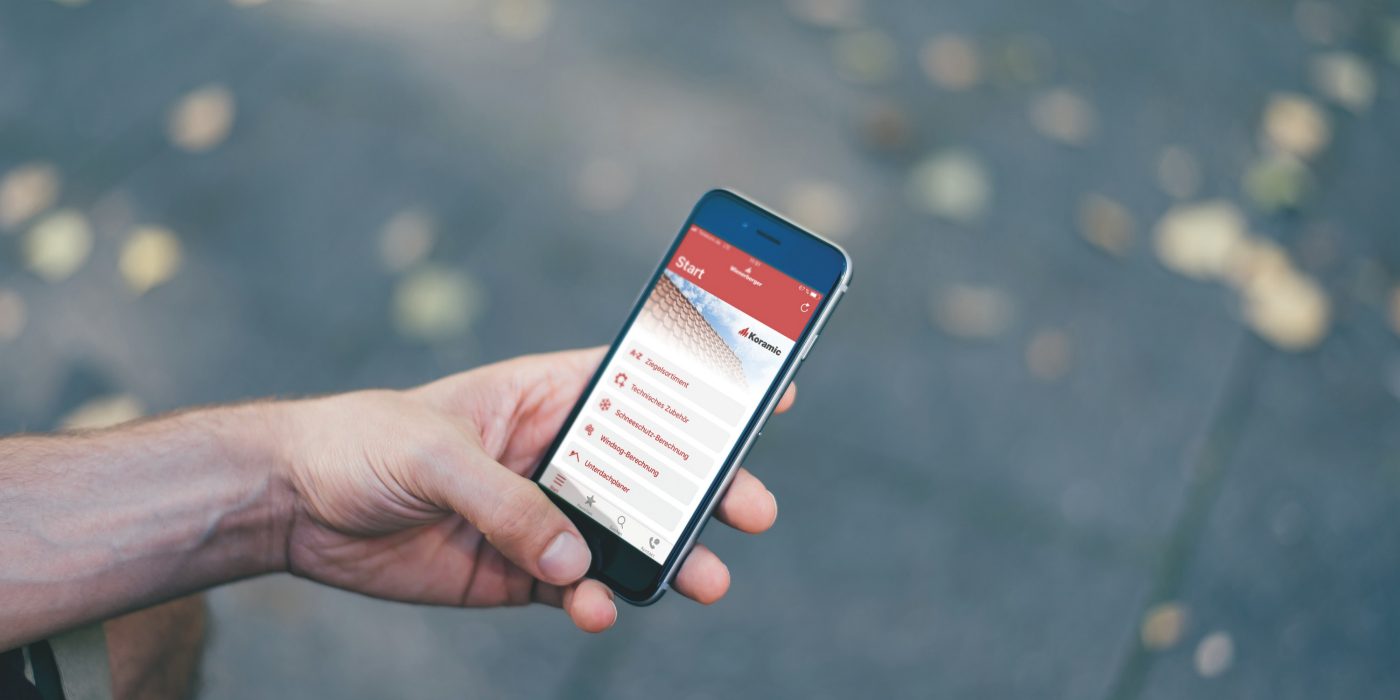 Male hand holding iPhone with Koramic App