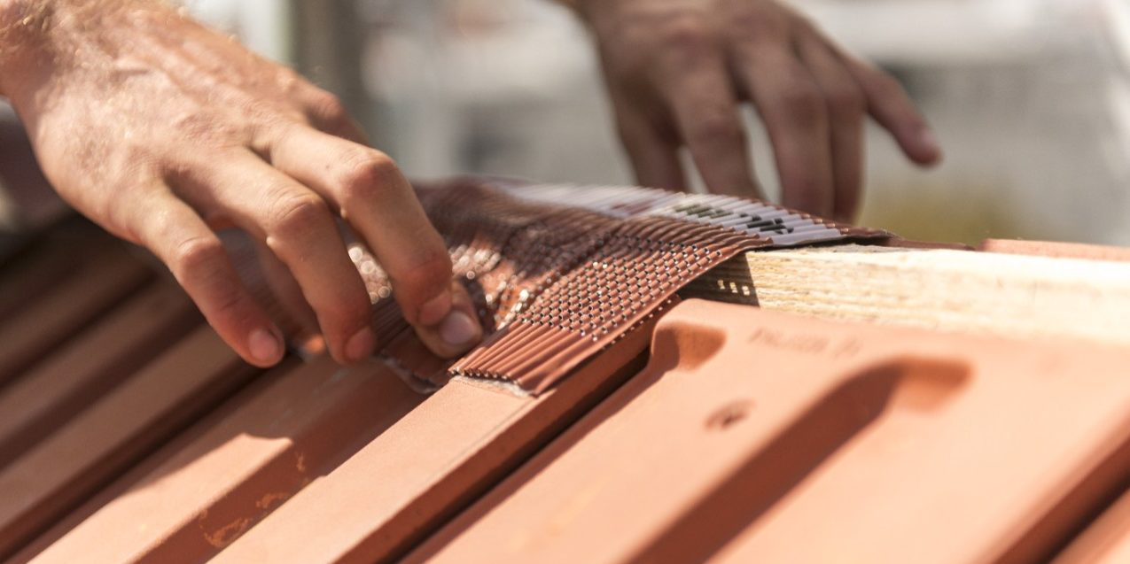 Roofer applying Alu-Grip Rol ridge and hip roll on ridge with bare hands