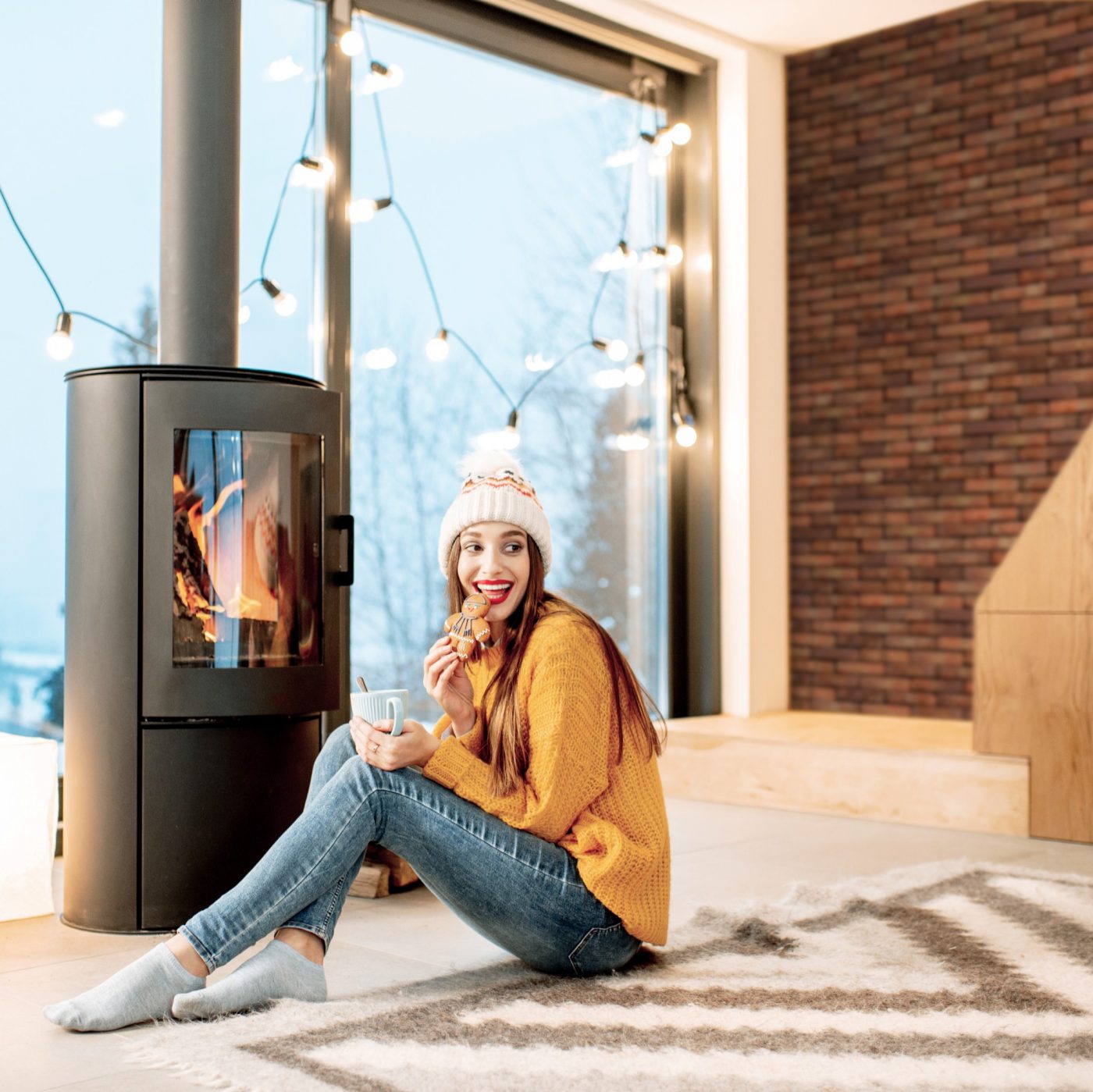 Frau sitzt vor Kamin mit Terca Wand im Hintergrund