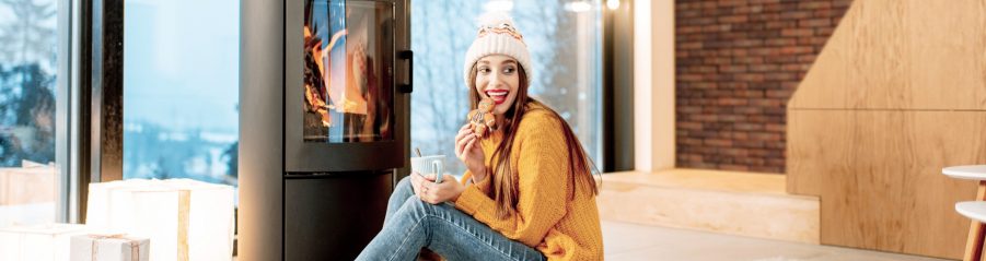 Frau sitzt vor Kamin mit Terca Wand im Hintergrund