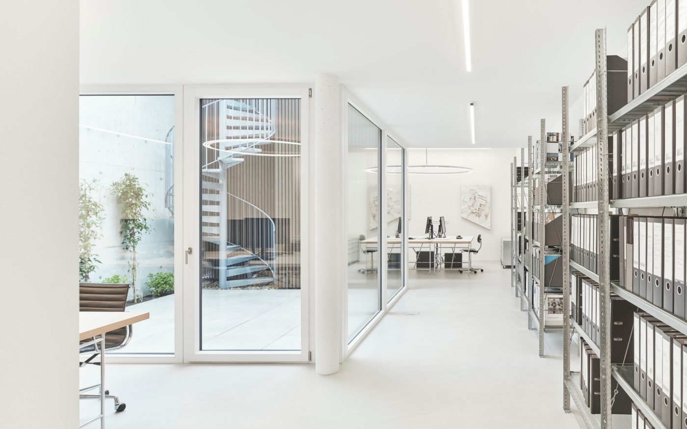Die in den Hang ragenden Büroflächen bieten großzügigen Platz für die sechs Mitarbeiter:innen in Stuttgart. Der eingelassene Lichthof dient als zweiter Rettungsweg und versorgt gleichzeitig die 24 Meter tiefe Büroeinheit mit Tageslicht.