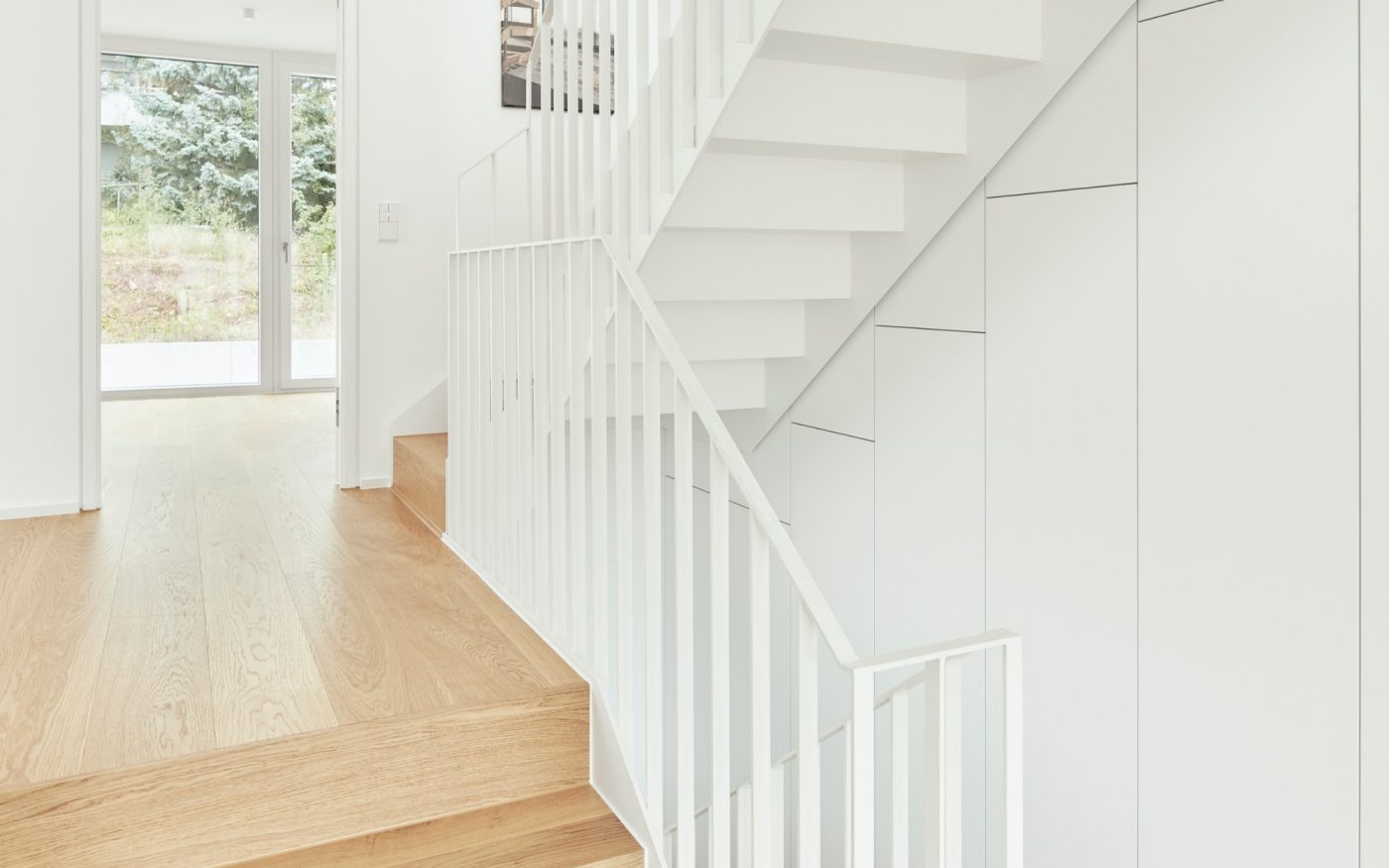 Ein wandbündig über drei Etagen in den Außenerker eingelassener Wandschrank schafft im Wohnbereich viel Stauraum.