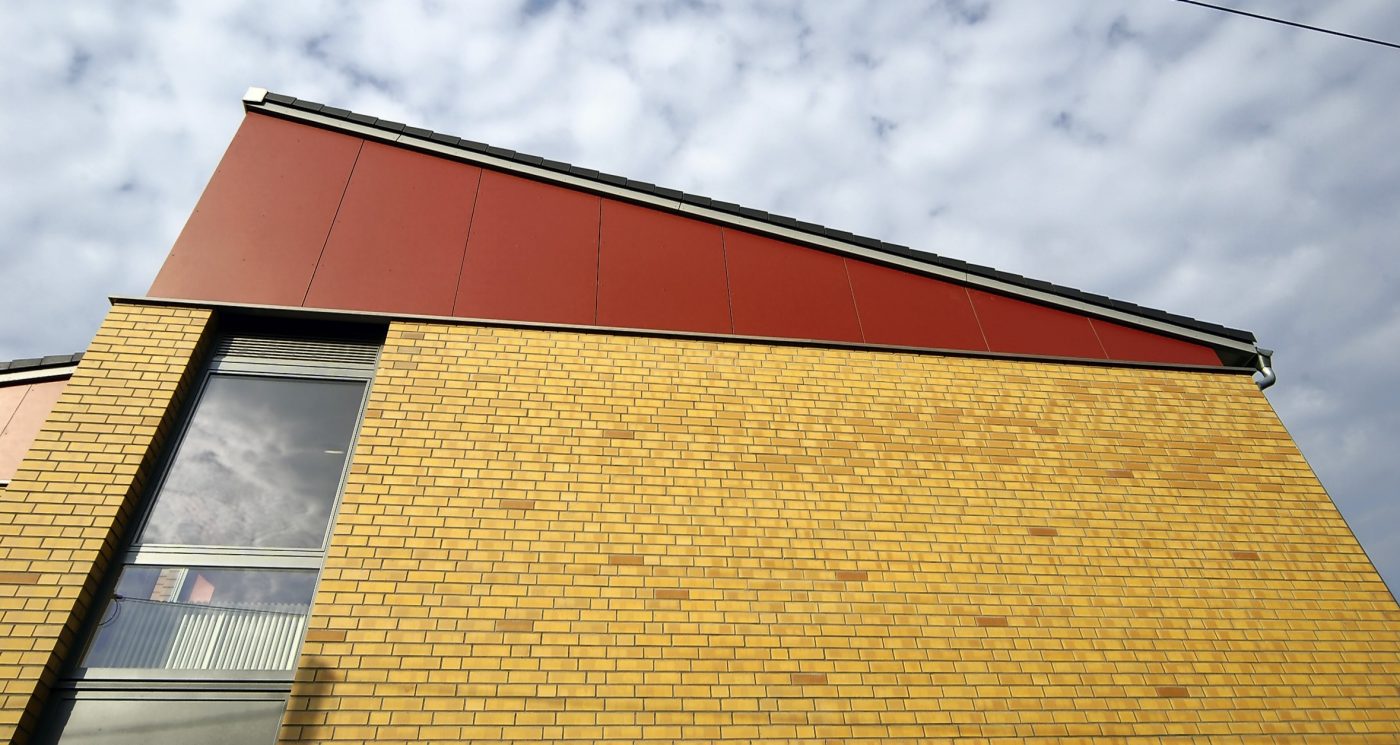 Building from the worm's-eye view, a window can be seen, the facade and a steep roof, Havelland, naturgelb geflammt, glatt, Lüneburg, rotbraun nuanciert, glatt