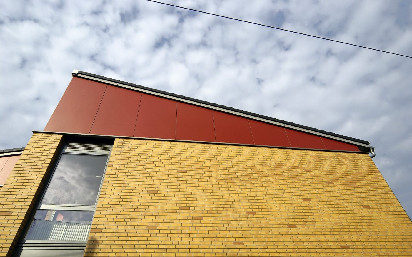 Building from the worm's-eye view, a window can be seen, the facade and a steep roof, Havelland, naturgelb geflammt, glatt, Lüneburg, rotbraun nuanciert, glatt