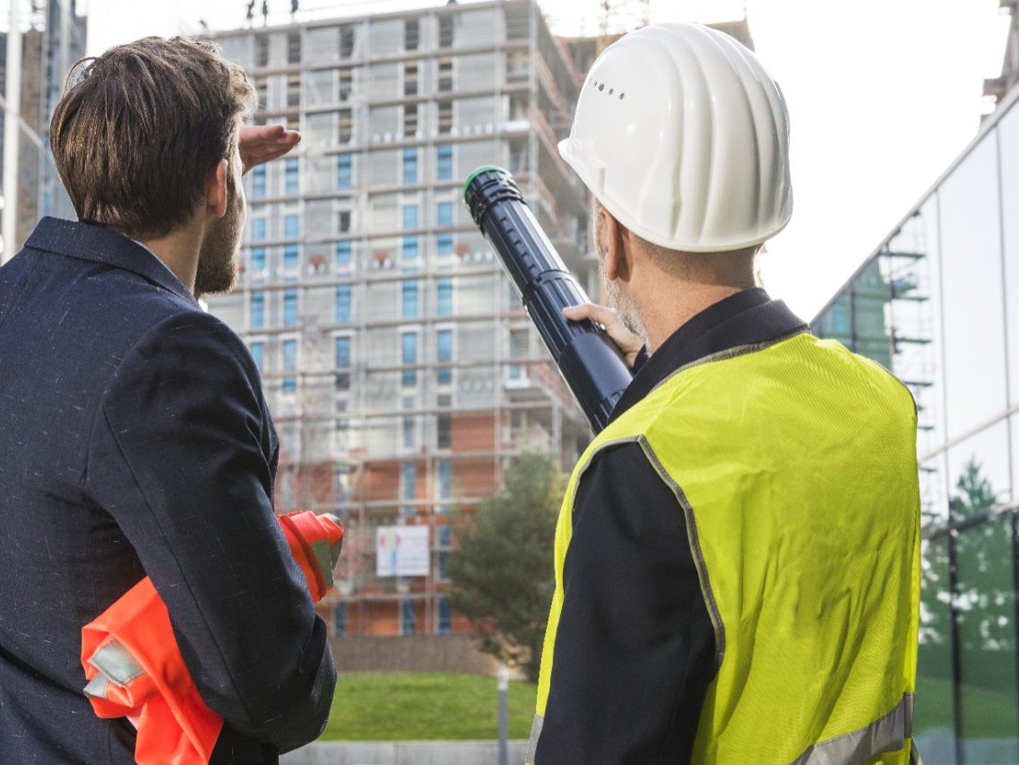 Businessman and architect talking about a new building project at a construction site