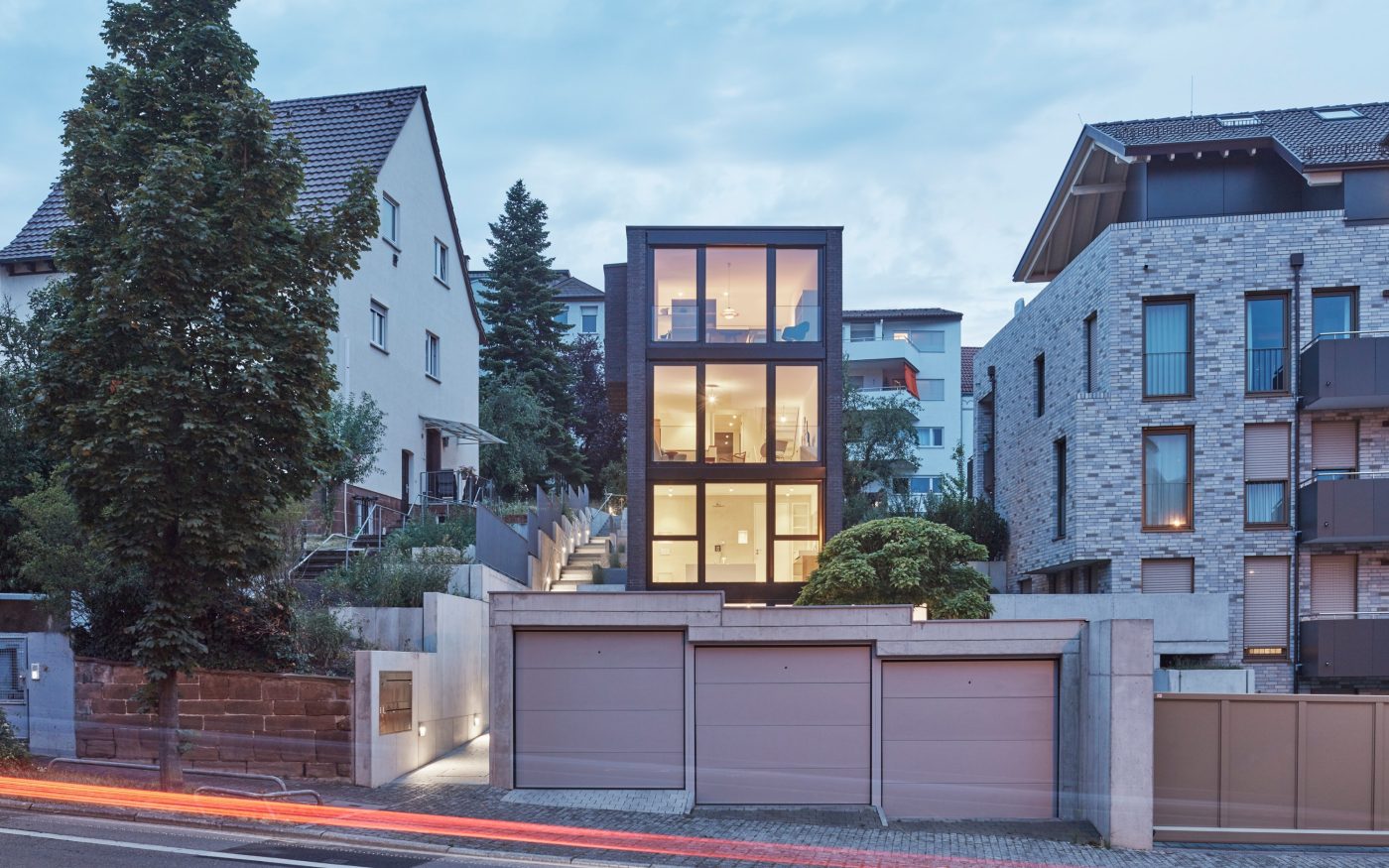 Von der Planckstraße aus verschwindet das breitere Untergeschoss hinter der höhengestaffelten Dreifachgarage.