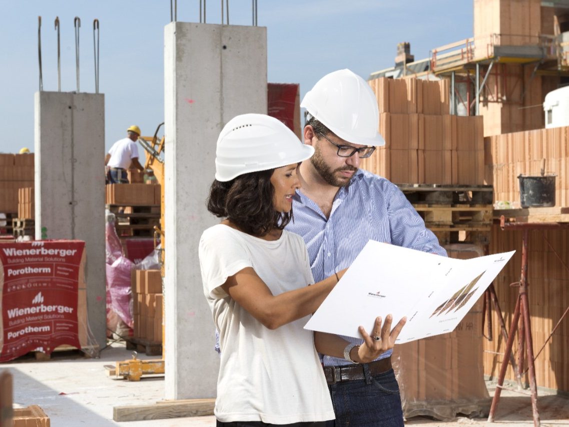 Architects with project folder surveilling construction site