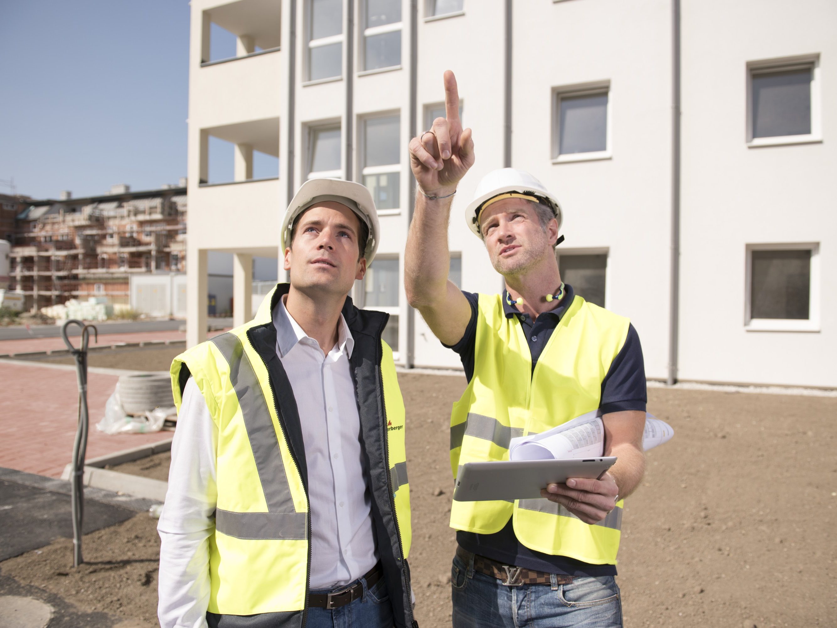 Building professionals monitoring status at construction site holding tablet and pointing finger, Fast Forward Commercial Excellence