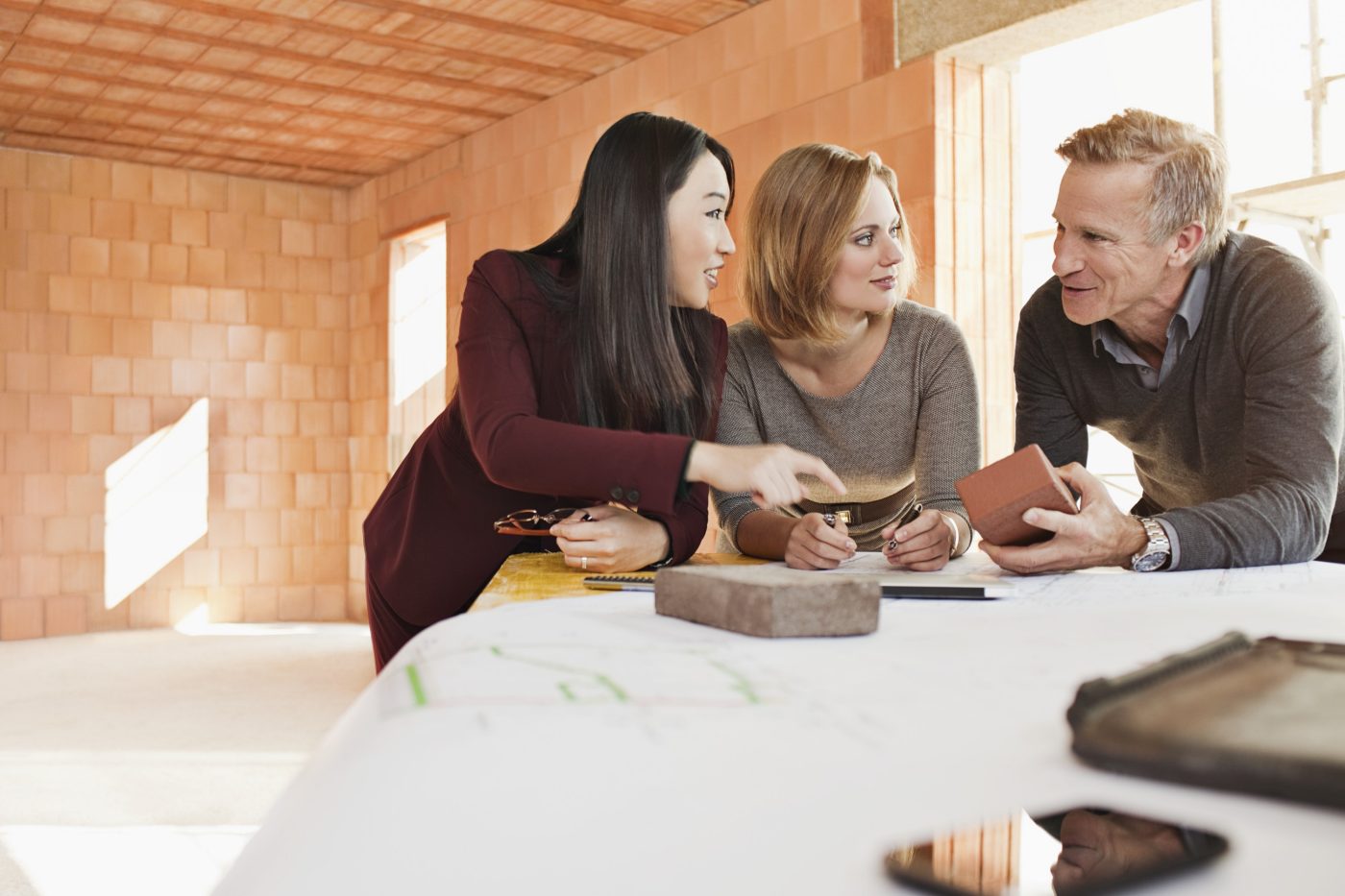 Group of people talking about their choice of building materials in unfinished building